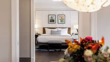 Ett hotellrum med en säng, sängbord, ett litet bord, en lampa, en vas med blommor och en inramad tavla på väggen.