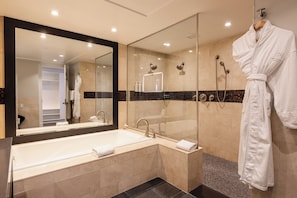 A modern bathroom with a large bathtub, a glass-enclosed shower, and a robe hanging on a rack.