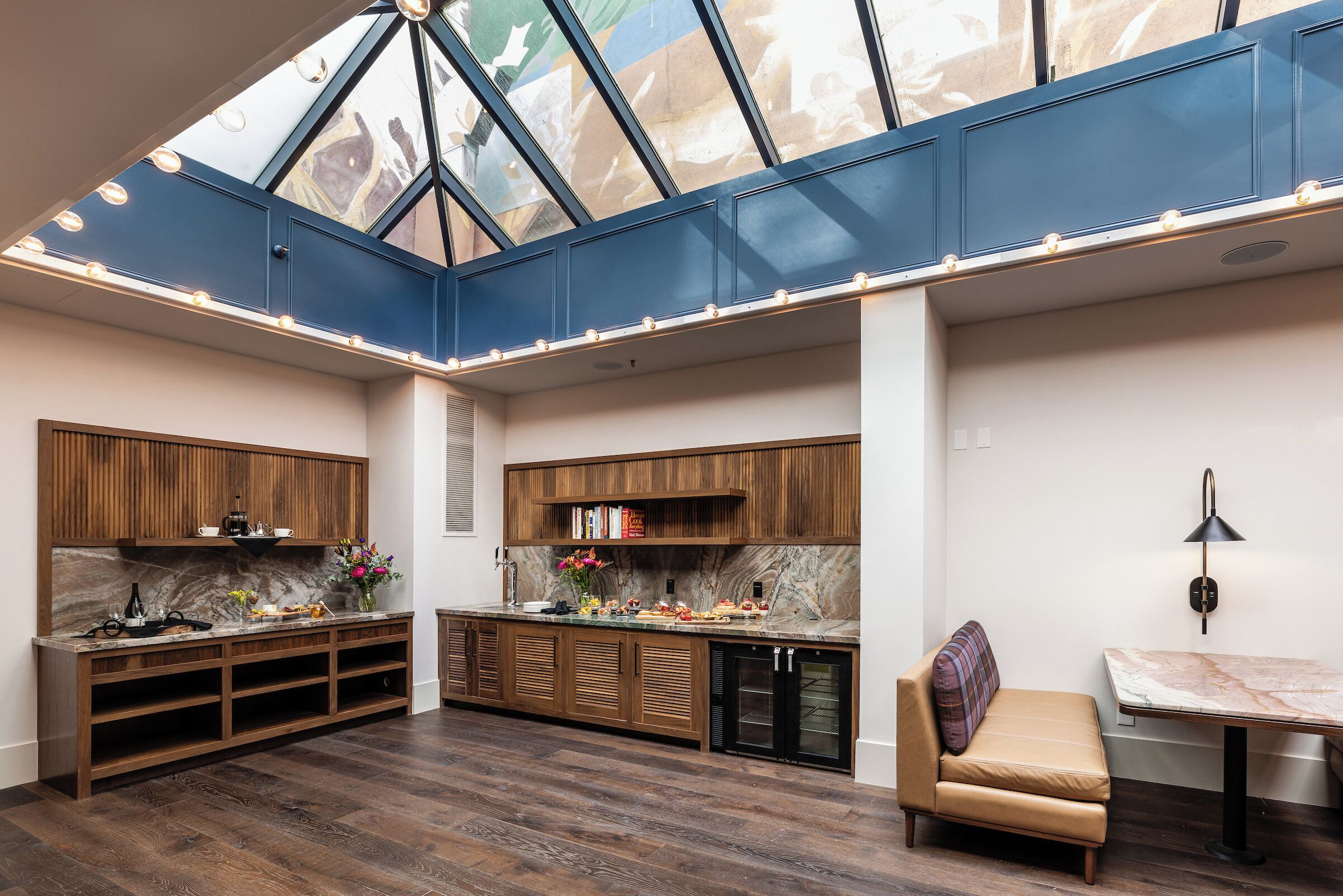 A modern kitchen with a skylight, wooden cabinets, and a built-in refrigerator.