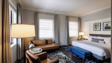 A hotel room with a bed, a sofa, a desk, and a chair.