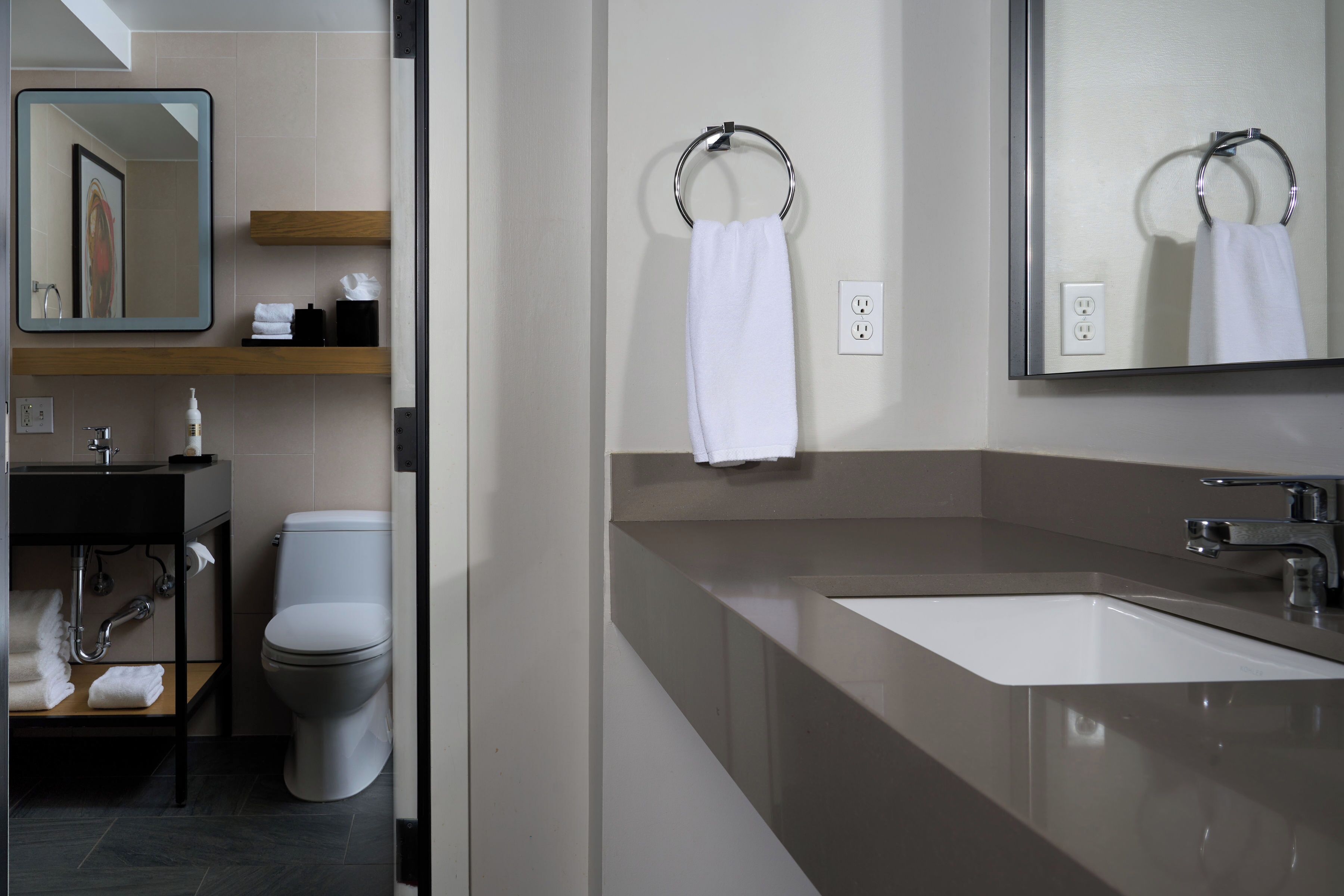A modern bathroom with a large mirror, a sink, and a toilet.
