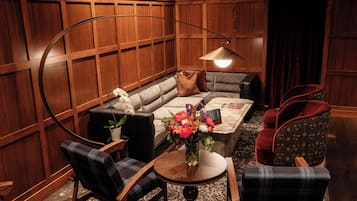 Una habitación acogedora con sofá, dos sillones, una mesita con un florero y una lámpara.