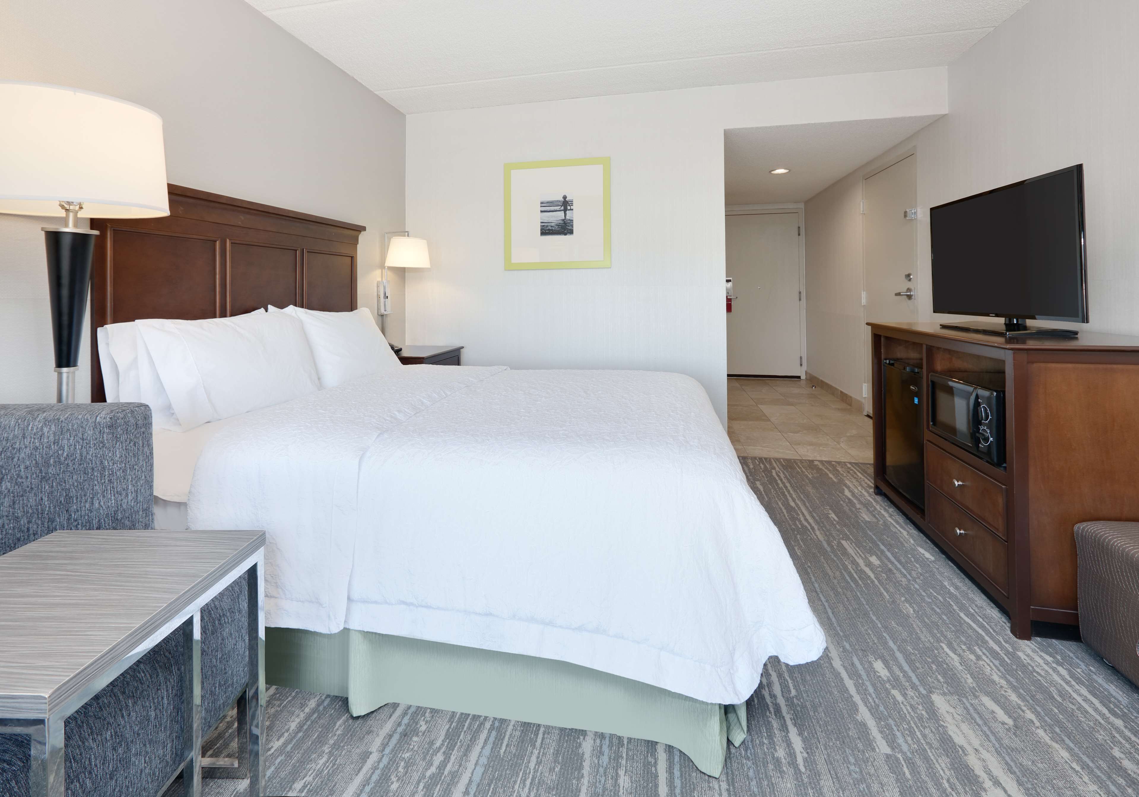 Habitación de hotel con una cama grande, televisión, escritorio y silla.