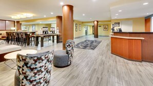 En hotellobby med en receptionsdisk, en sittgrupp och en plats där man kan hämta kaffe.