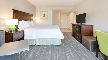 A hotel room with a bed, a desk, a chair, a television, and a wardrobe.