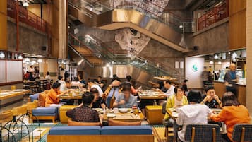 A spacious restaurant with multiple dining areas, including booths and tables, and a central staircase.
