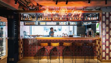 A bar area with a neon sign, a bartender, and a tiled backsplash.