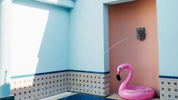 Une piscine avec un flotteur en forme de flamant rose et une statue de flamant rose blanche.