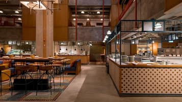 A spacious restaurant with high ceilings, exposed beams, and a mix of seating areas including tables and booths.