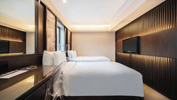 A modern hotel room with a large bed, a desk with a chair, a flat-screen TV, and a large mirror.