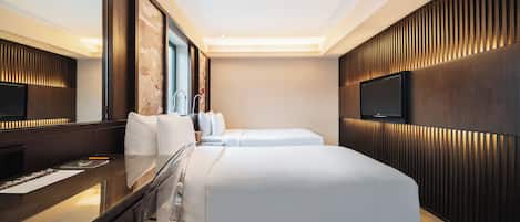 A modern hotel room with a large bed, a desk with a chair, a flat-screen TV, and a large mirror.