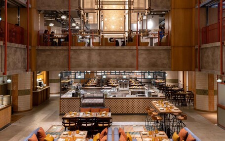A spacious restaurant with high ceilings, multiple dining areas, and a central kitchen.