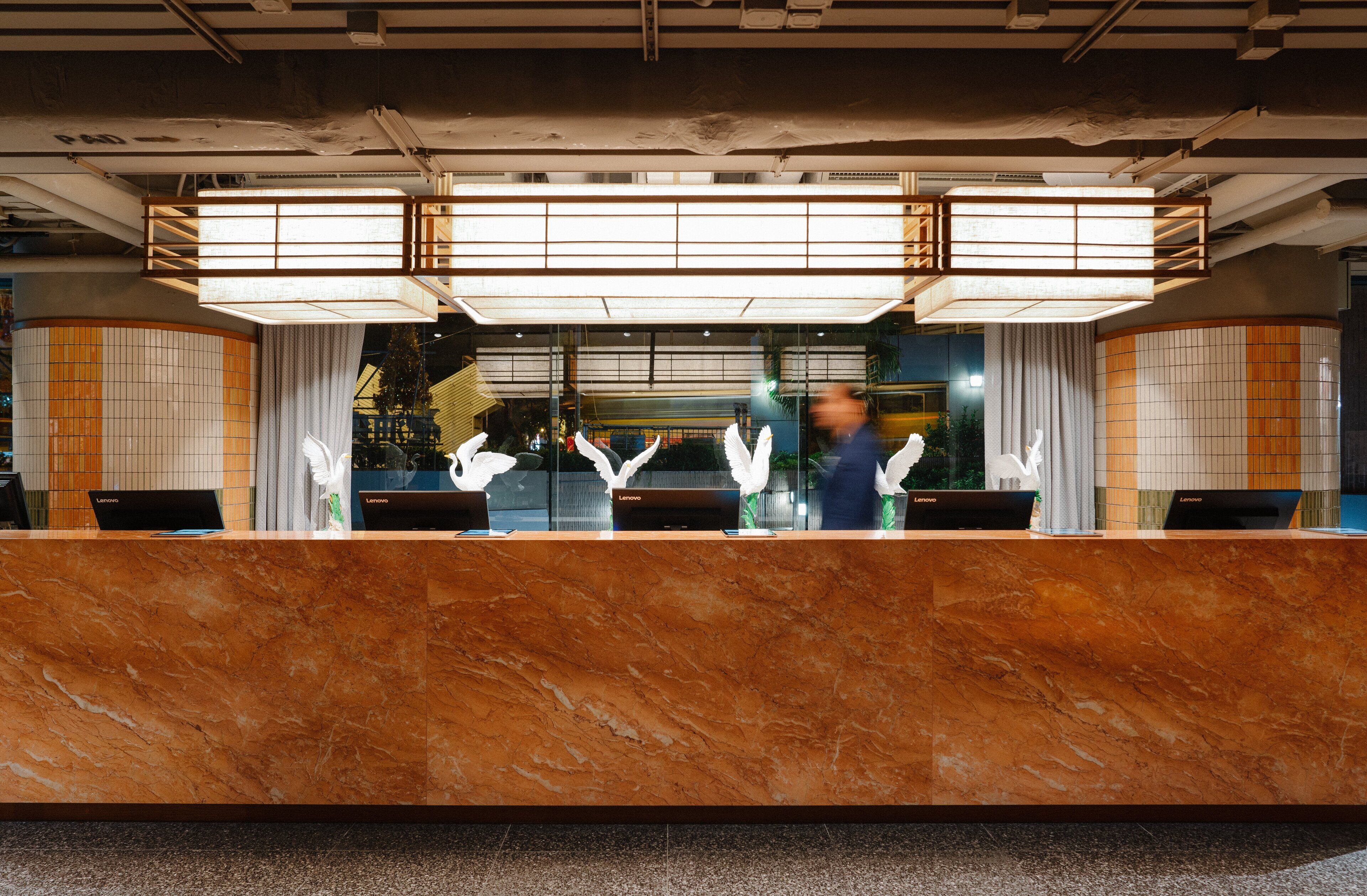 A reception desk with a marble top, a large window, and a modern light fixture above.