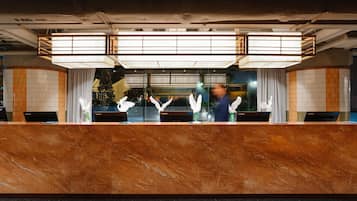 A reception desk with a marble top, a large window, and a modern light fixture above.