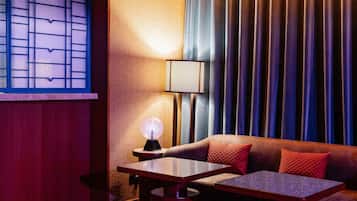 Ein gemütliches Zimmer mit einer Couch, Hocker, einem Tisch und einer Lampe.