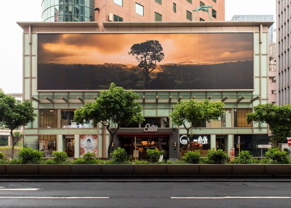 A building with a large billboard featuring a tree and sunset. - Eaton HK (Kowloon)