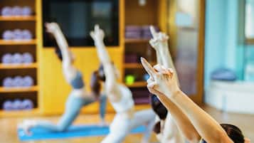 Clase de yoga en una habitación con suelo de madera y un ventanal grande.