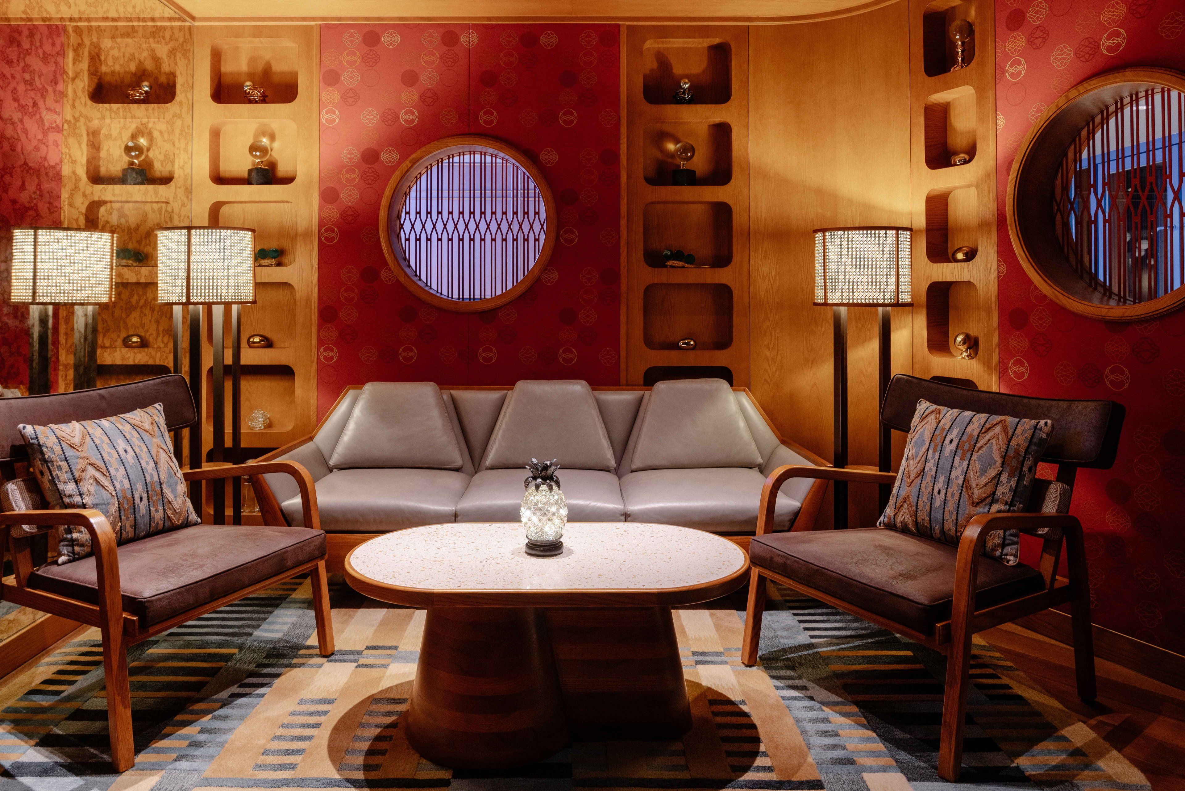 A room with a brown leather sofa, two armchairs, a round coffee table, and two floor lamps.