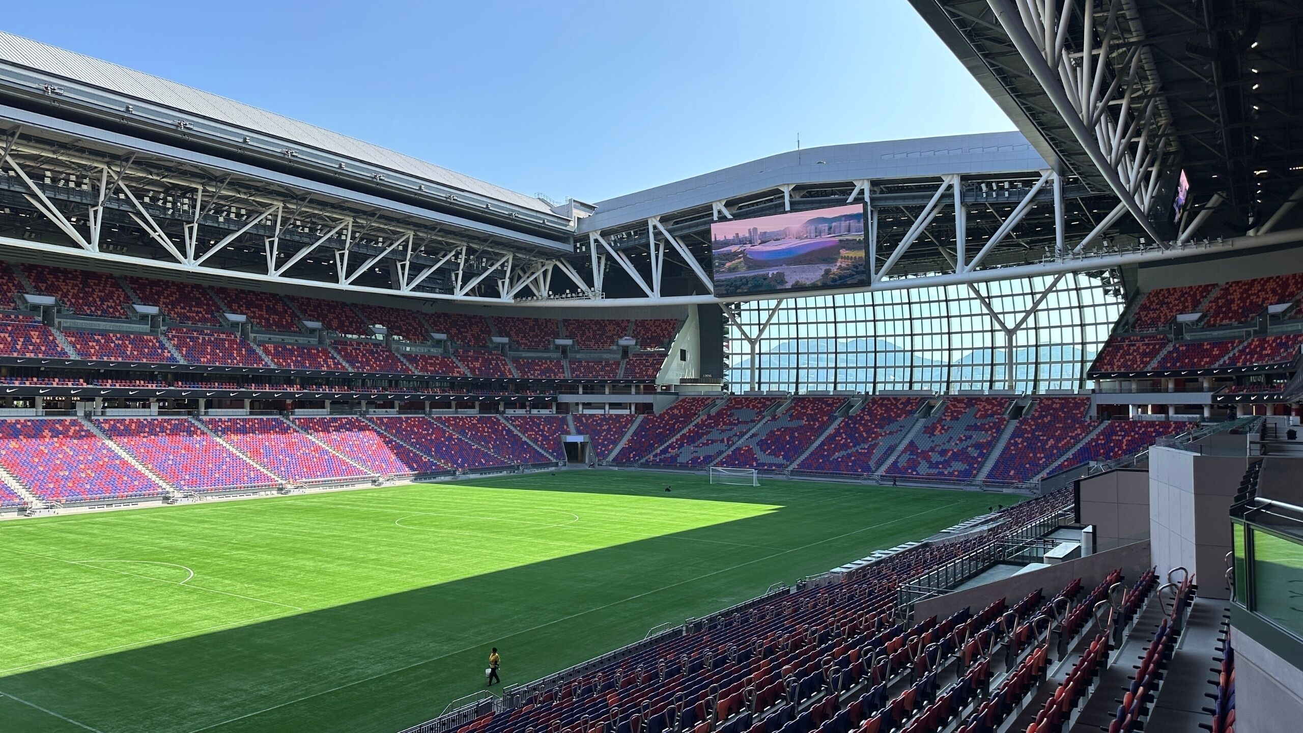 Un estadio con múltiples niveles de asientos, un amplio campo central y una estructura de techo elevada.