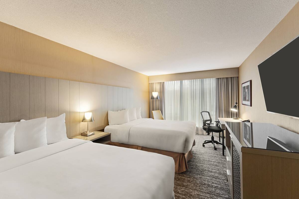 Une chambre d’hôtel avec deux lits, un bureau et une chaise.