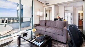 A modern hotel room with a large window, a grey sofa, a glass coffee table, and a black office chair. - Executive Hotel Vancouver Airport (Richmond)