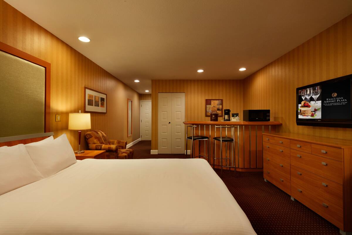 Une chambre d’hôtel avec un grand lit, un bureau avec une chaise, une télévision et un mini-bar.