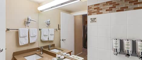 Un baño moderno con un espejo grande, dos lavamanos, un perchero para toallas y una zona de ducha.