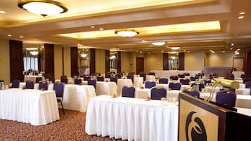 Un salón de conferencias con varias mesas, sillas y un atril con un logotipo.