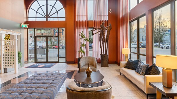 A spacious lobby with a large seating area, a reception desk, and a view of the street through large windows. - Executive Hotel Vancouver Airport (Richmond)