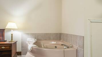 A bathroom with a bathtub, a vanity with a lamp, and a door.