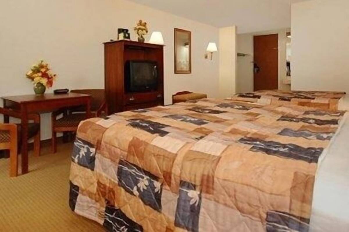 Una habitación de hotel con una cama grande, un escritorio, un televisor y un espejo.