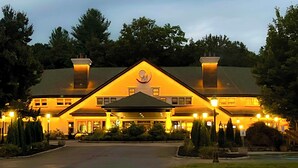 A large, two-story building with a prominent central entrance, surrounded by well-maintained landscaping and trees. - Chateau Merrimack Resort & Spa (Tyngsboro)