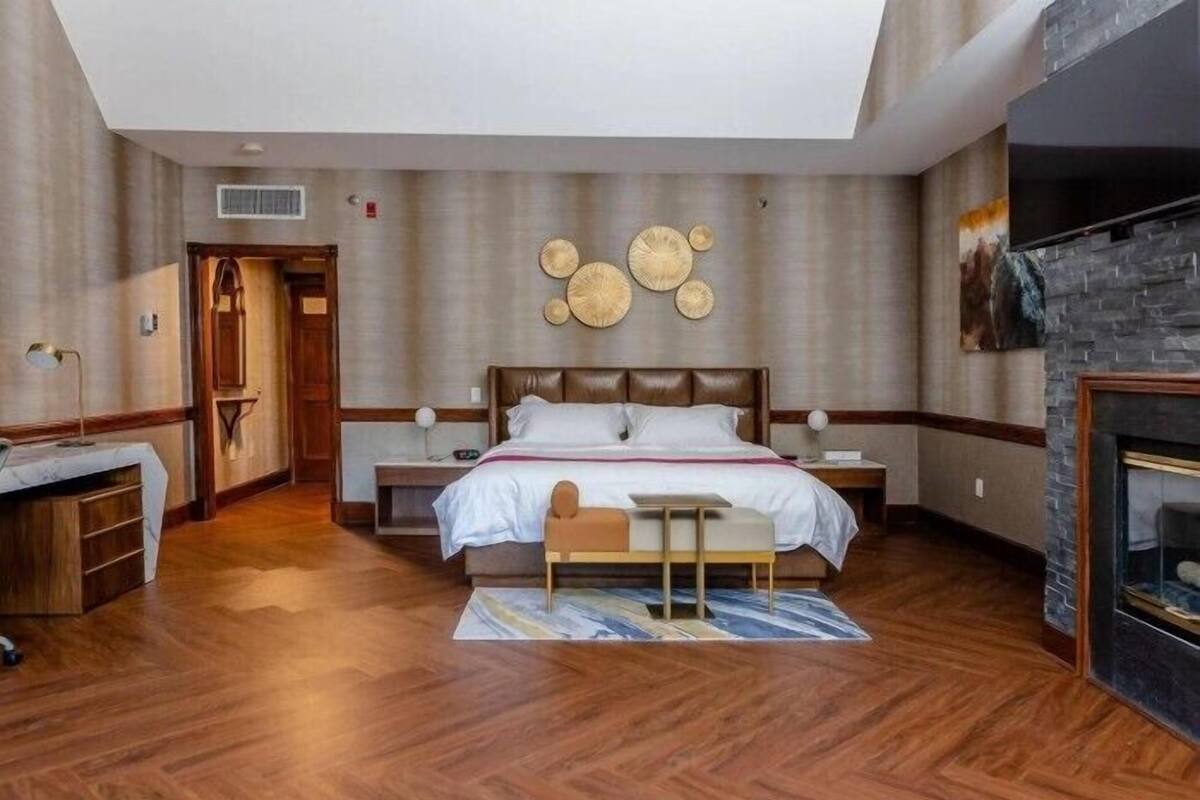 Ein modernes Hotelzimmer mit einem großen Bett, einem kleinen Tisch, einem Kamin und Blick ins Freie.