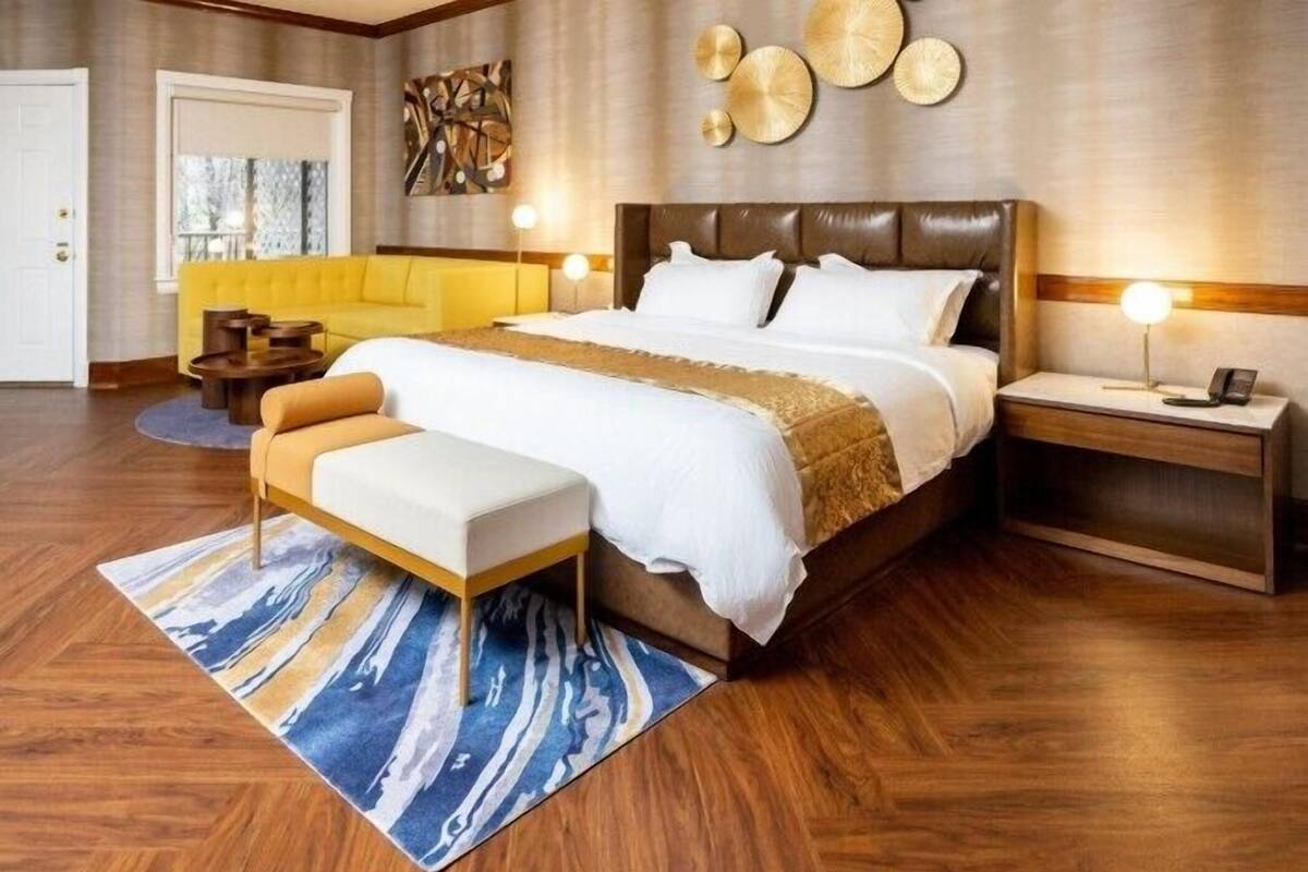 Ein modernes Schlafzimmer mit einem großen Bett, Nachttischen, einer Bank und einer Wanddekoration.