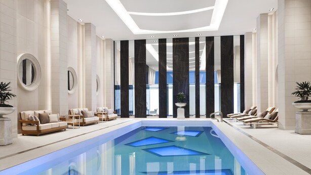 Un espace piscine intérieur moderne, avec des jeux de lumière géométriques, des chaises longues et une vue sur l’extérieur.