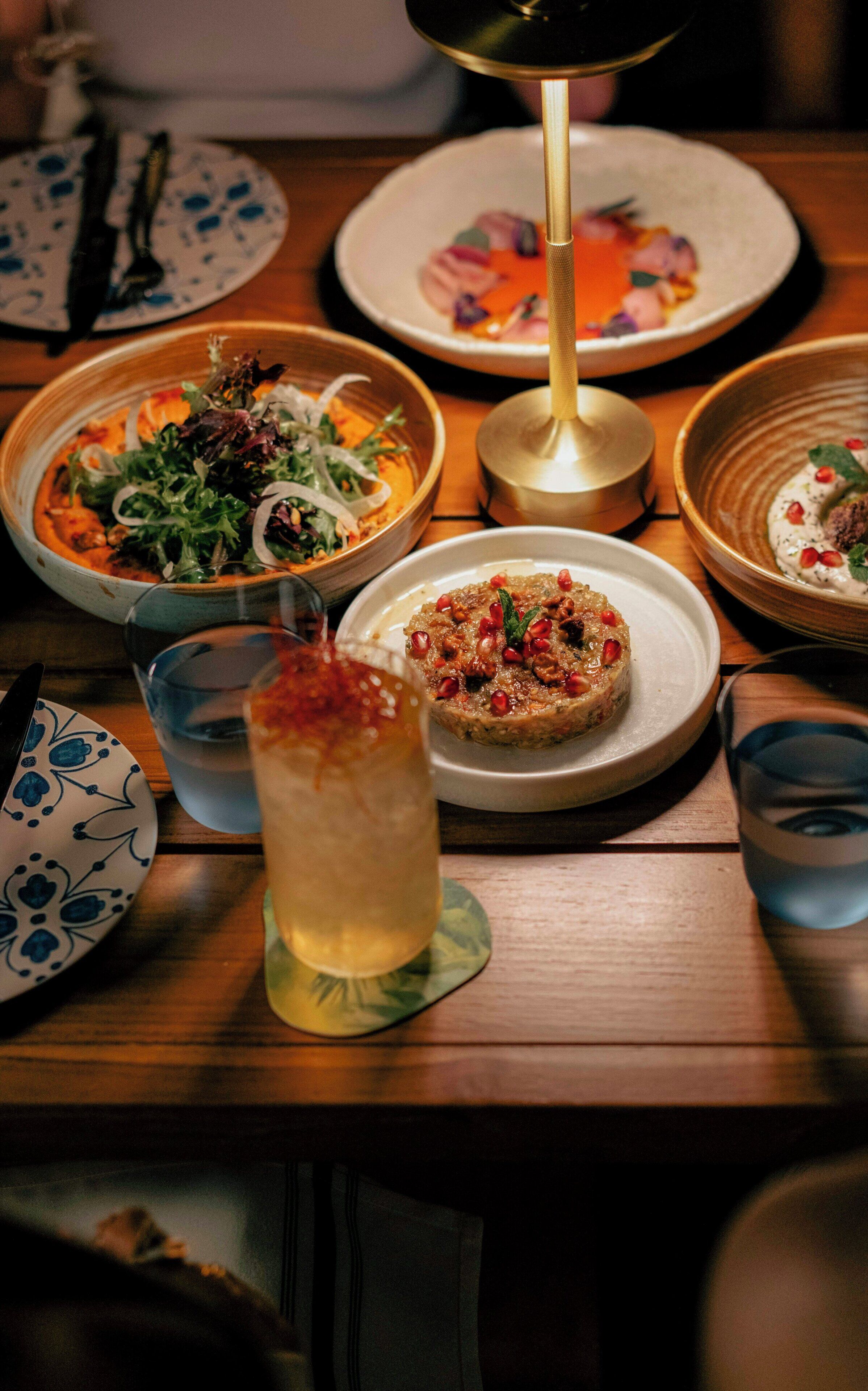 Una mesa de comedor con diversos platos, un vaso de agua y una vela.