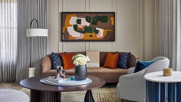 A modern living room with a sofa, a coffee table, and a chair. There is a painting on the wall and a lamp on the ceiling.