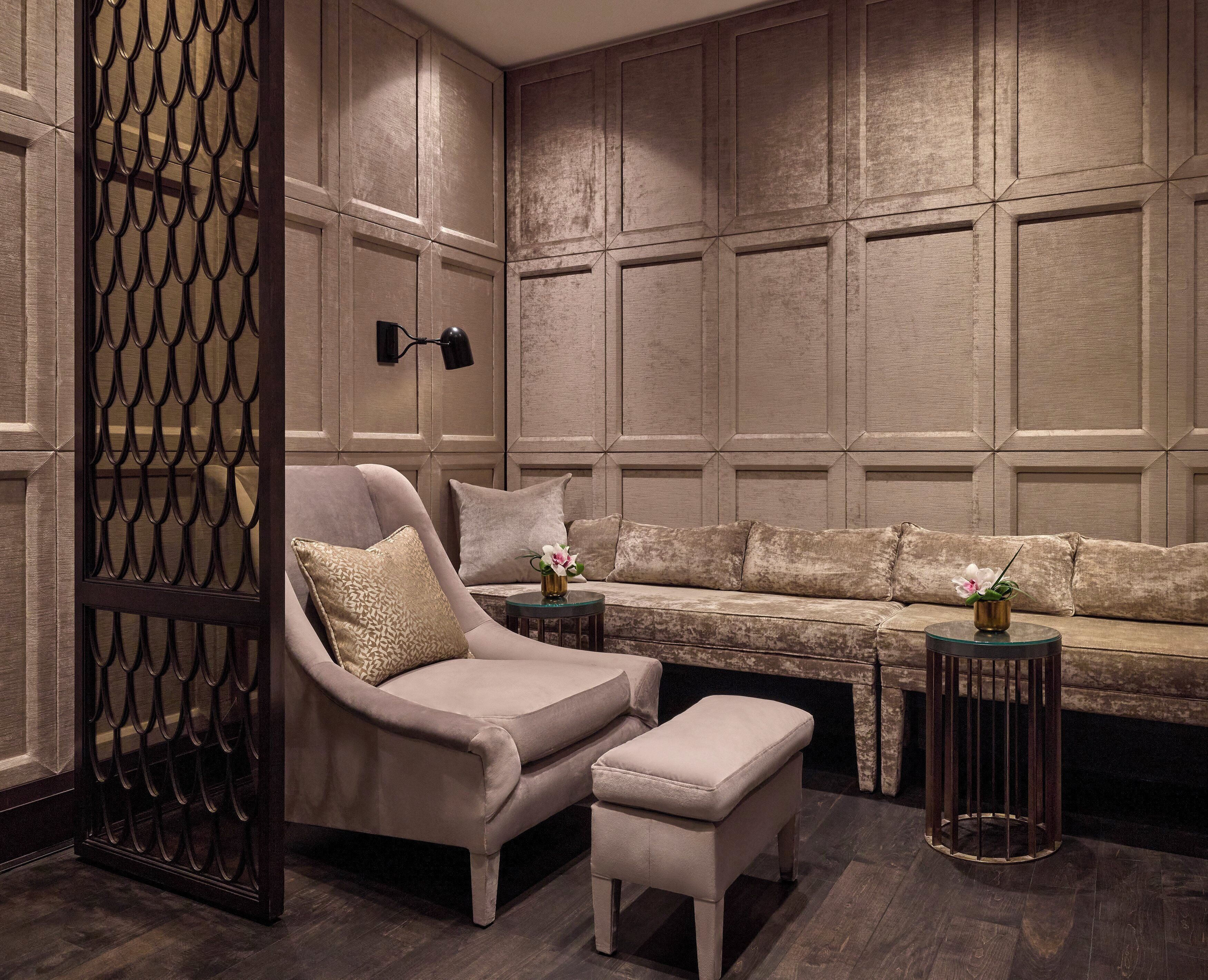 Una sala de estar moderna con sofá, sillón, reposapiés, un panel decorativo y una mesita con un florero.