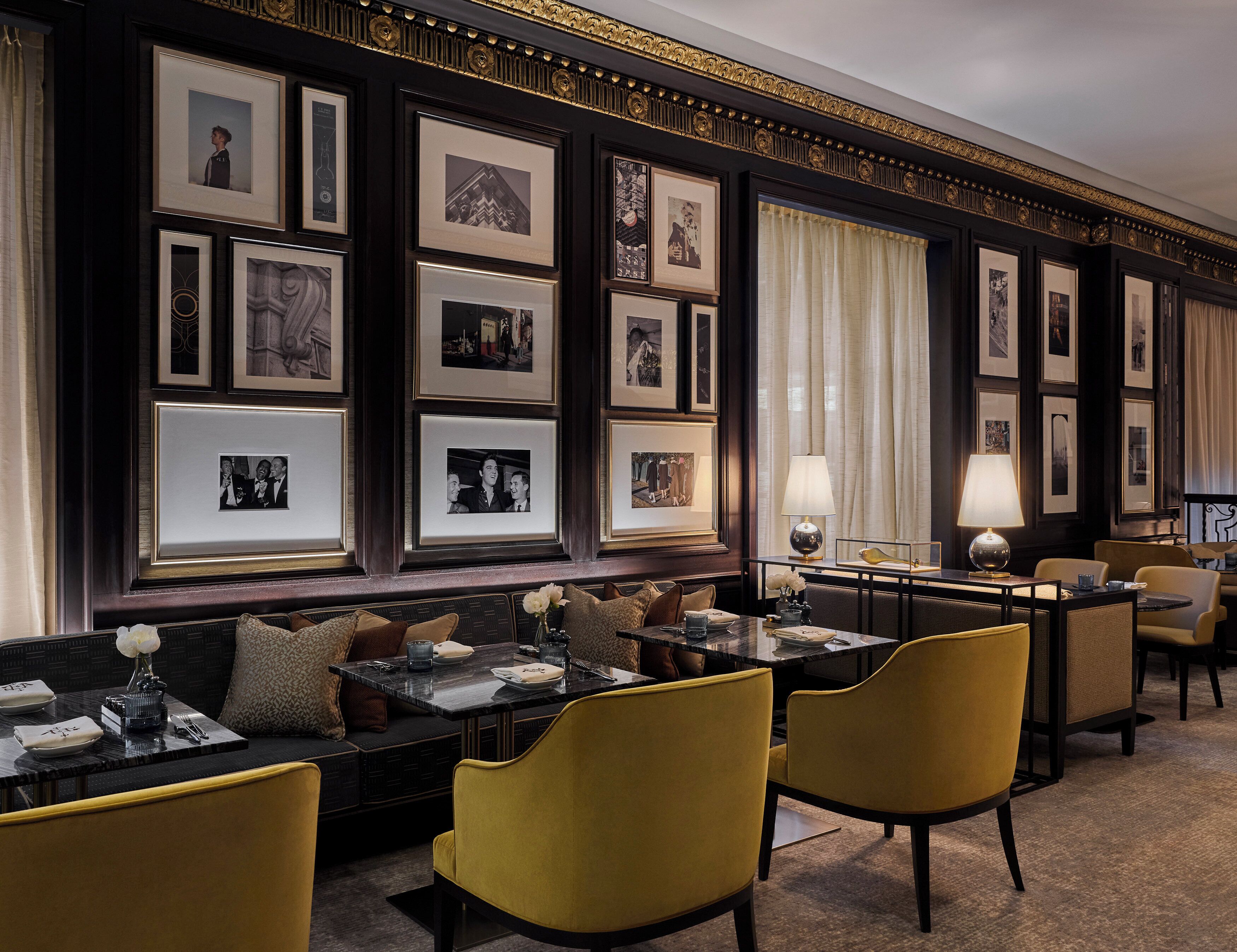 A formal dining area with a long table, multiple framed pictures on the wall, and classic decor.