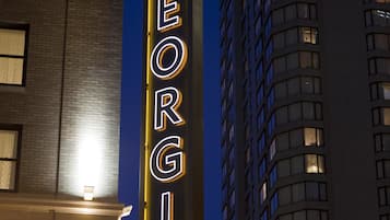 Une enseigne d’hôtel avec le nom « GEORGIA » écrit en lettres lumineuses, fixée sur la façade d’un immeuble.
