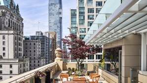 Une terrasse sur le toit, avec une table et des chaises en bois, un espace repas et une vue sur le panorama urbain.