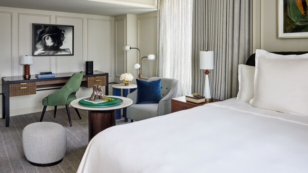 A hotel room with a bed, a desk, a chair, a round table, and a lamp. - Rosewood Hotel Georgia (Vancouver)