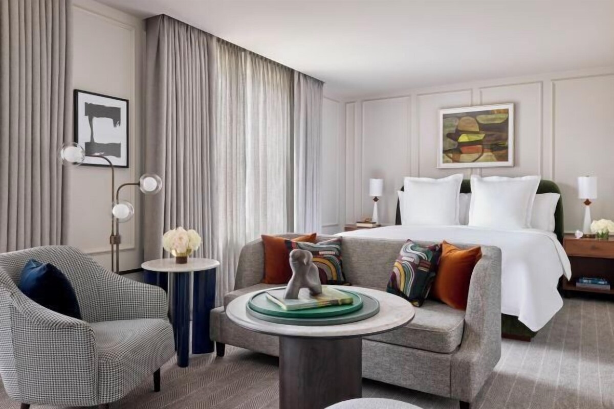 A hotel room with a bed, a sofa, a small round table, and a chair.