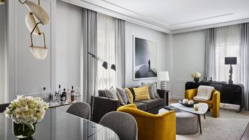 A modern living room with a glass coffee table, a sofa with yellow and grey cushions, a black piano, and a large framed picture on the wall.