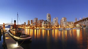 Une vue urbaine sur le front de mer, avec un pont imposant, de hauts immeubles et un bateau amarré.