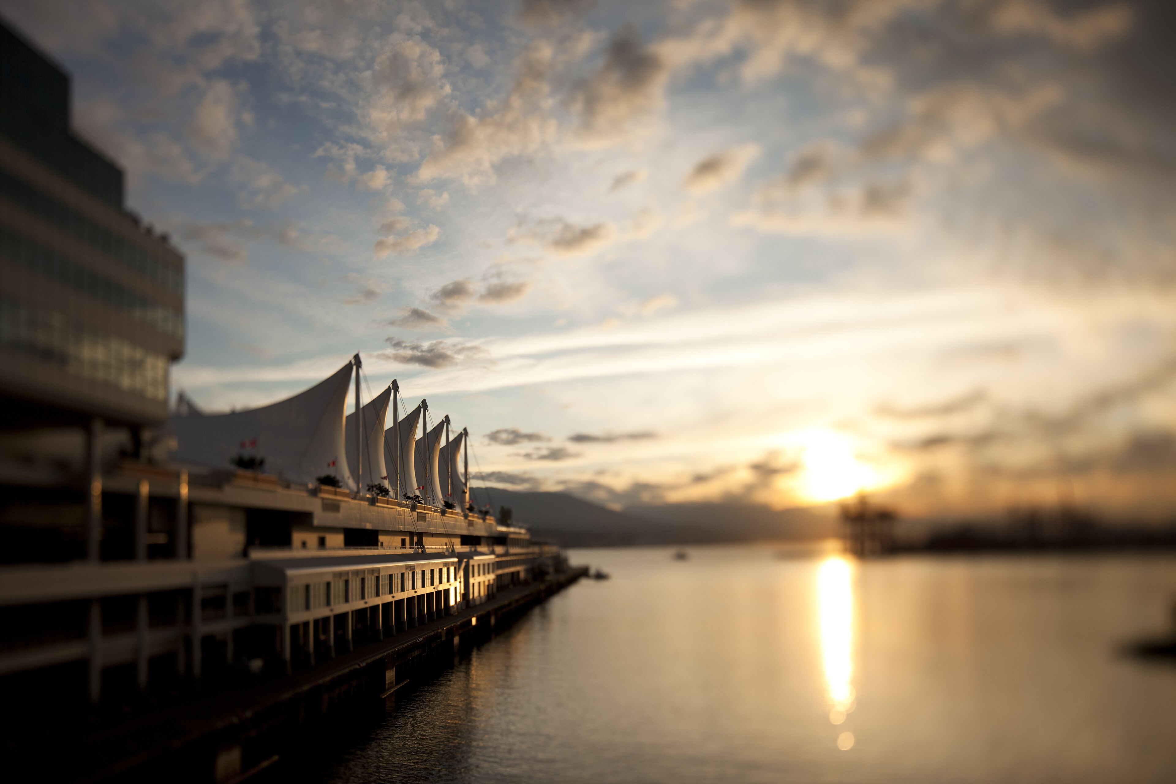 A waterfront hotel with a modern design, featuring a long pier extending into the water.