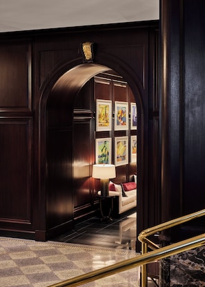 A lobby with a dark wooden reception desk, a lamp, and framed artwork on the wall. - Rosewood Hotel Georgia (Vancouver)