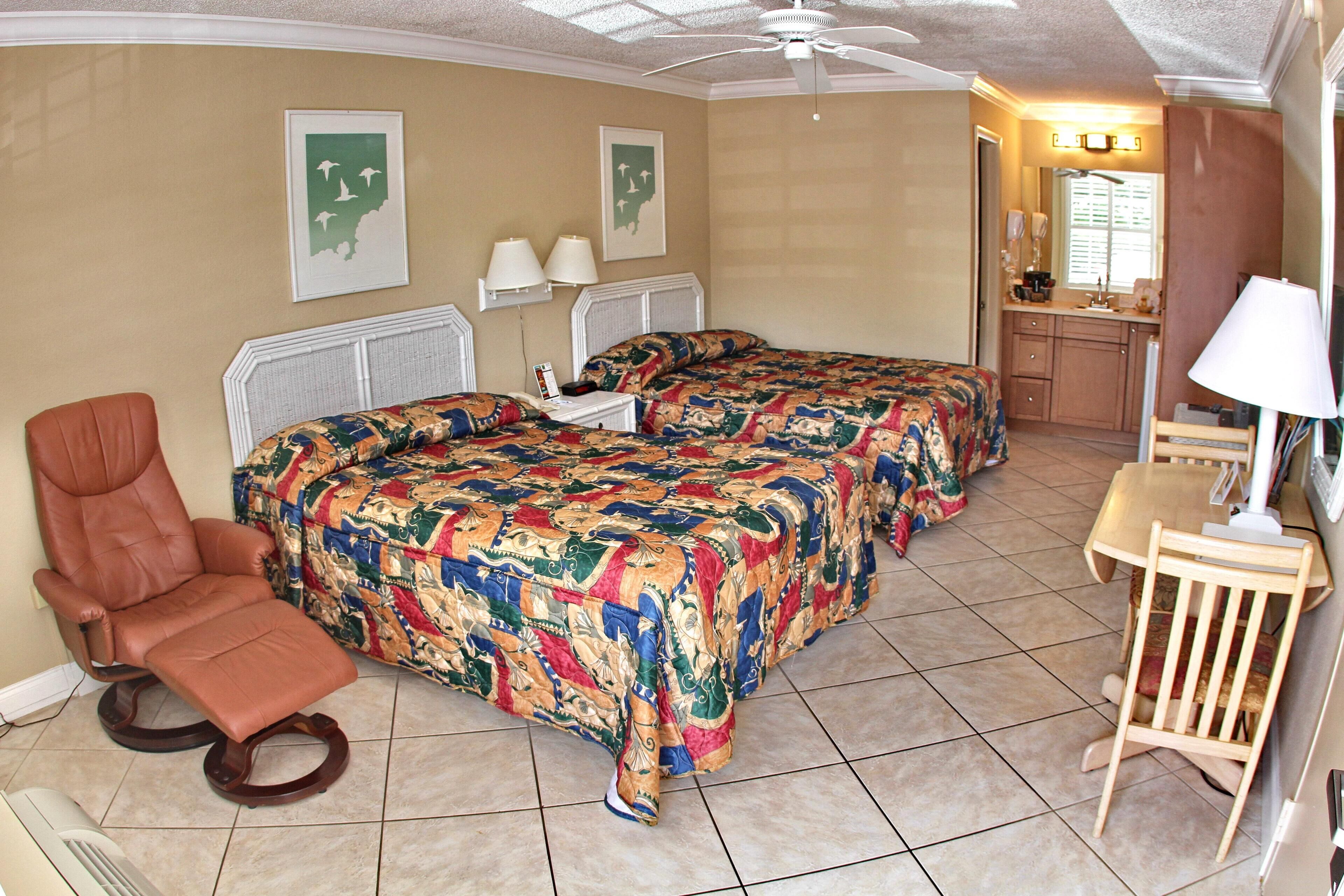 Ein Hotelzimmer mit einem großen Bett, einem Sessel, einem Schreibtisch und einem Badezimmer.
