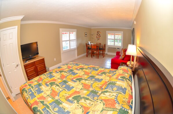 A bedroom with a large bed, a TV, a desk, and a chair.