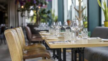 Un restaurante con una larga mesa dispuesta para comer, con sillas de cuero y una decoración interior moderna.